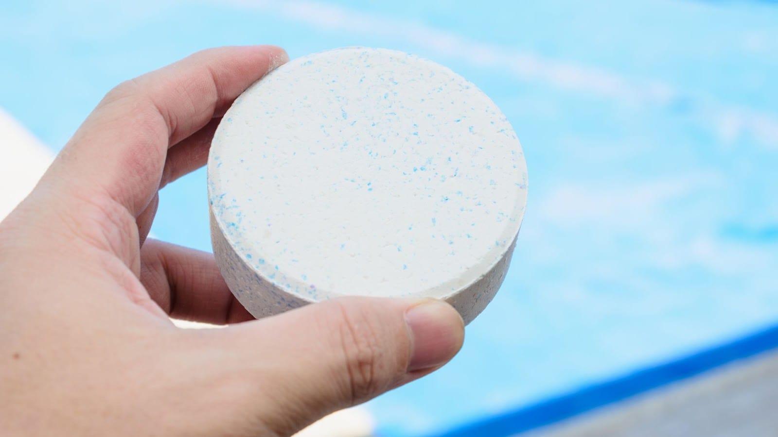 Person holding a large chlorine tablet for pool