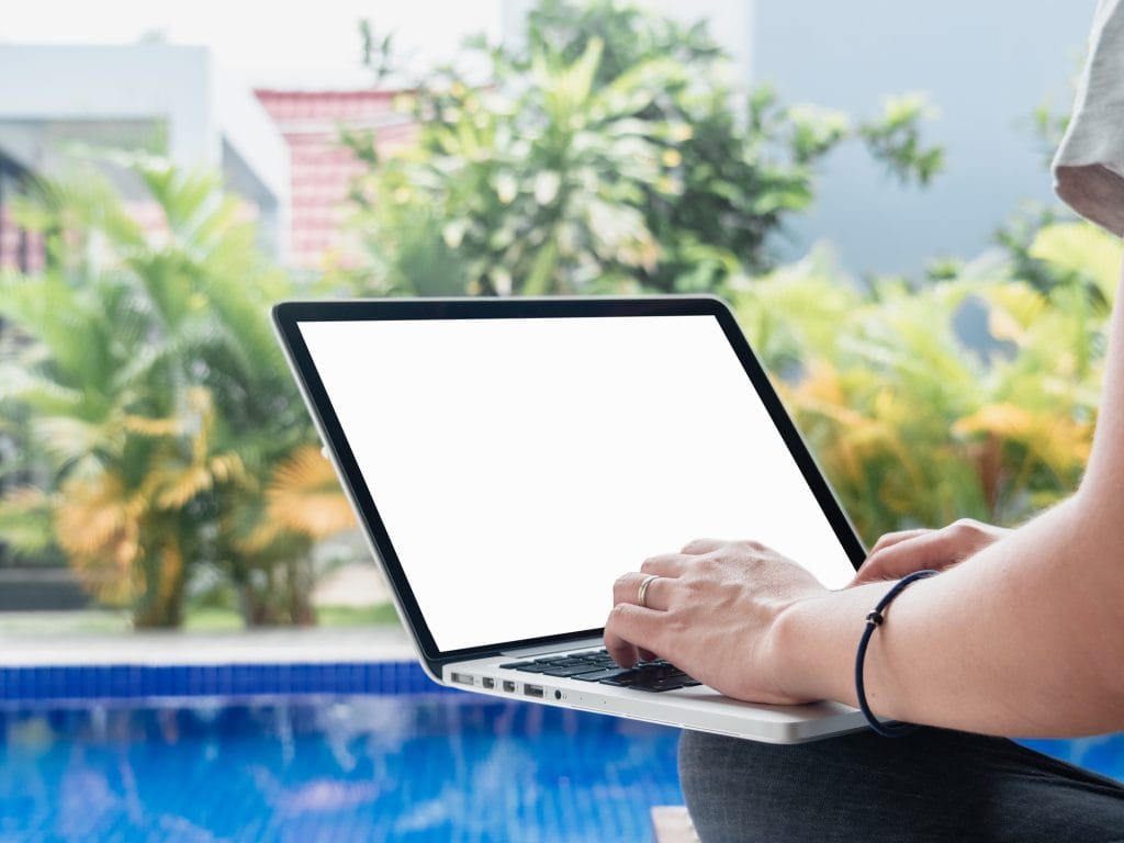 Woman with a laptop by a pool doing pool and spa marketing
